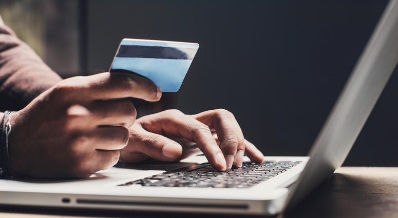 hands holding a credit card to a computer keyboard