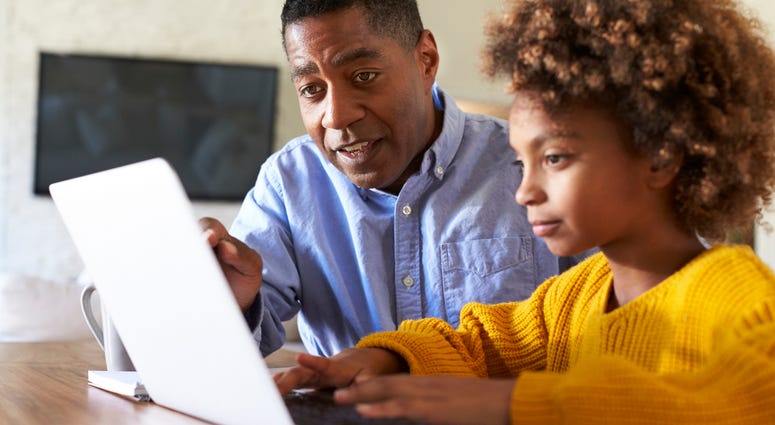 A tutor instructs a child at a computer.