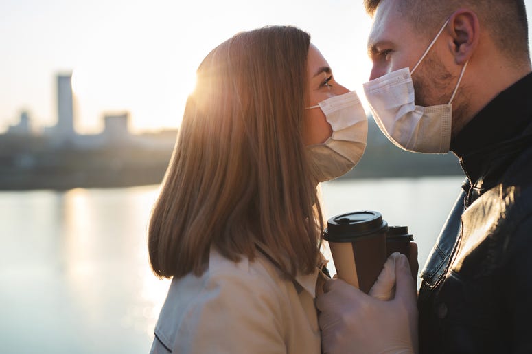 Couple wearing masks kissing near lake