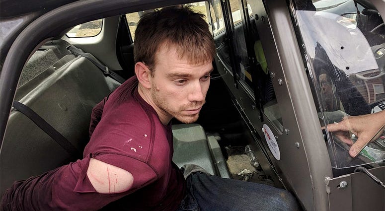 In this photo released by the Metro Nashville Police Department, Travis Reinking sits in a police car after being arrested in Nashville, Tenn., on Monday, April 23, 2018.