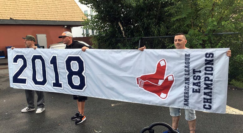 friends hold a banner they found in Somerville, Mass., that proclaims the Boston Red Sox are the 2018 American League East Champions friends hold a banner they found in Somerville, Mass., that proclaims the Boston Red Sox are the 2018 American League East Champions