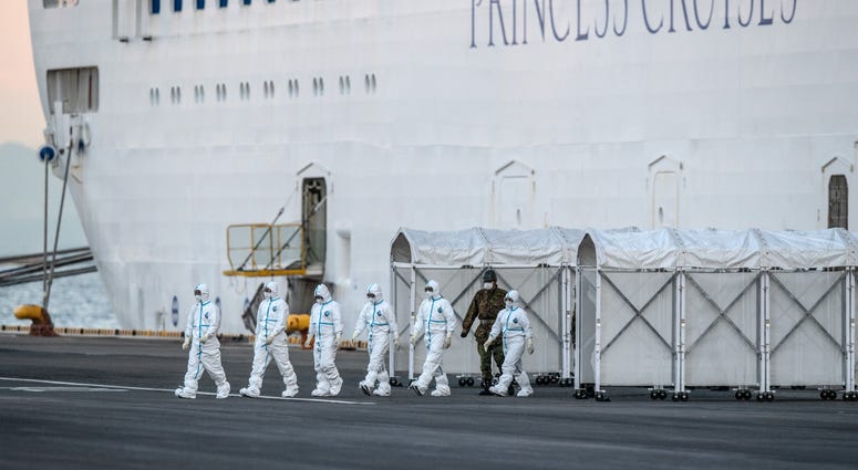 Emergency workers in protective clothing exit the Diamond Princess cruise ship at Daikoku Pier where it is being resupplied and newly diagnosed coronavirus cases taken for treatment as it remains in quarantine