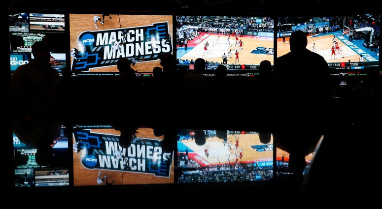 In this March 15, 2018 photo, people watch coverage of the first round of the NCAA college basketball tournament. In this March 15, 2018 photo, people watch coverage of the first round of the NCAA college basketball tournament.