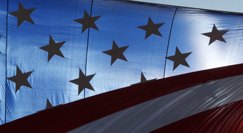 An American flag blows in the hot breeze during the opening on Day 1 of Fair St. Louis on the grounds of the Gateway Arch in St. Louis on July 4, 2018.
