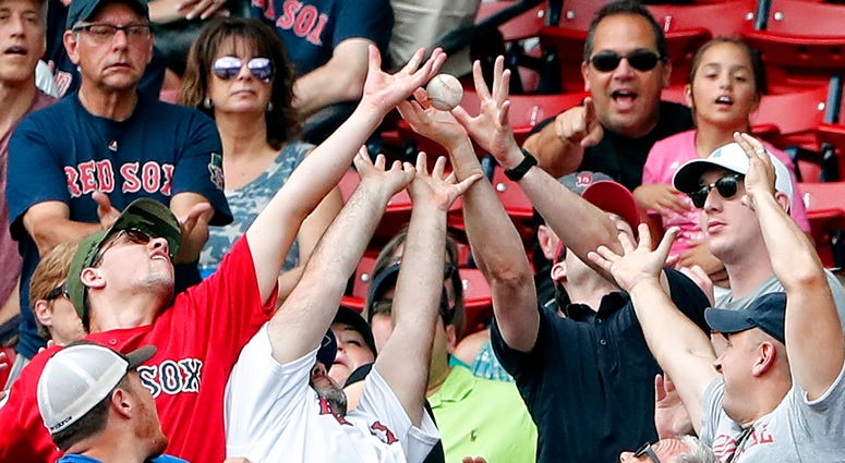 Boston Red Sox fans reach for a foul ball in the seats Boston Red Sox fans reach for a foul ball in the seats