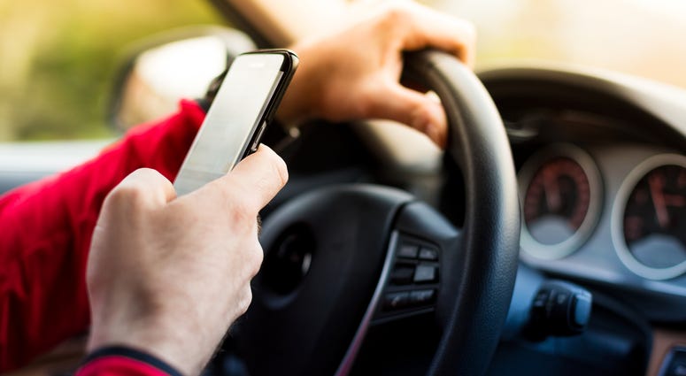 A person is texting while driving. A person is texting while driving.