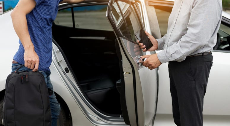 taxi, uber, lyft Taxi driver greeting his passengers with their luggage on the sidewalk of a modern city