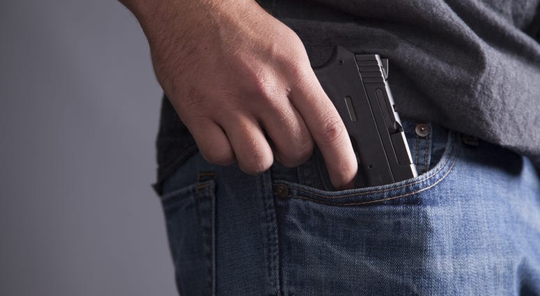 gun, pocket A man legally carries a firearm in his pocket for protection.