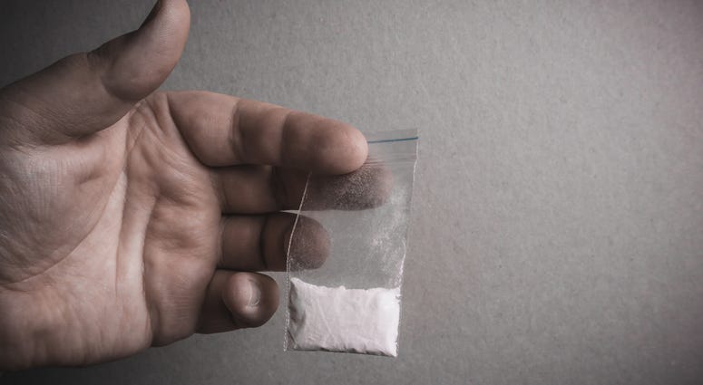 Mans hand holds plastic packet with cocaine powder or another drugs. Drug dealer selling drugs junkie