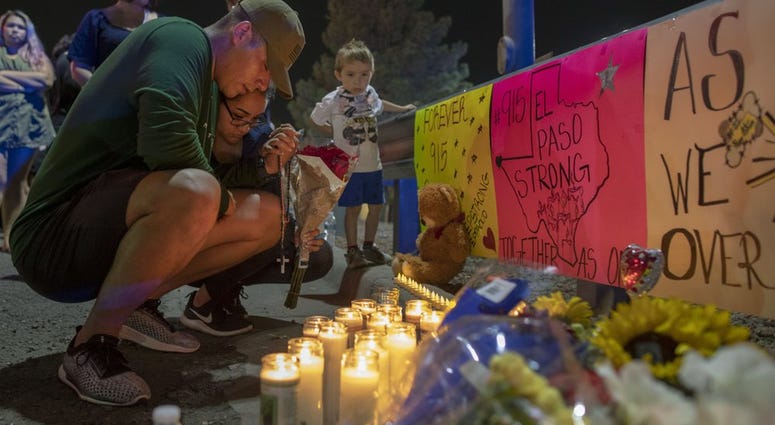 people mourn at a vigil after a shooting in an El Paso Walmart