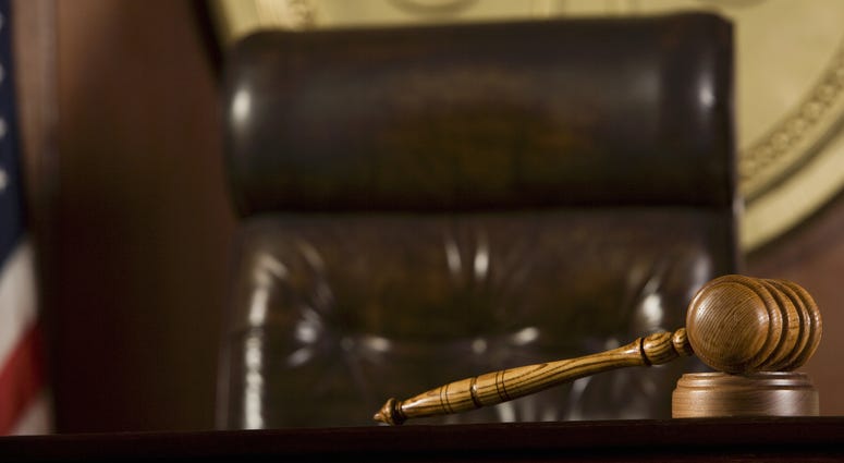 Wooden gavel lying on table by judge's chair in courtroom