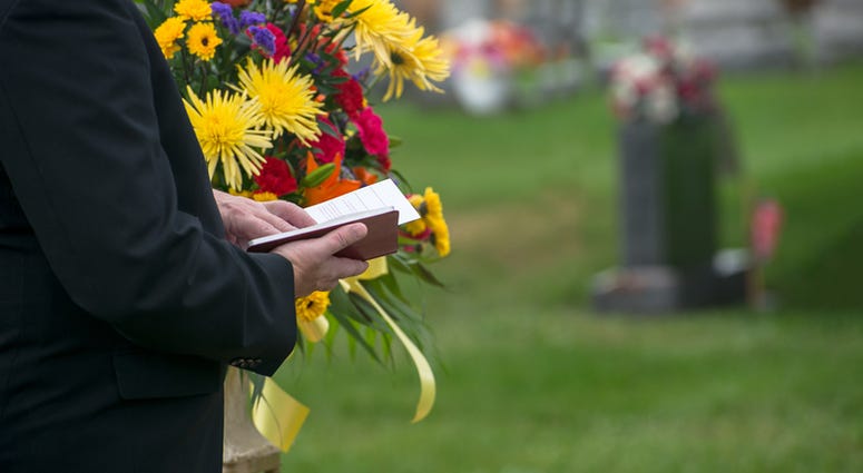 funeral A pastor or minister reads from the Bible during a funeral burial memorial service at a cemetery. Death and grief are a fact of life.