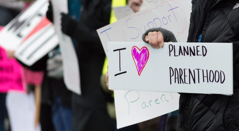 Planned Parenthood, protest A group of people holding signs supporting Planned Parenthood during a pro choice demonstration.
