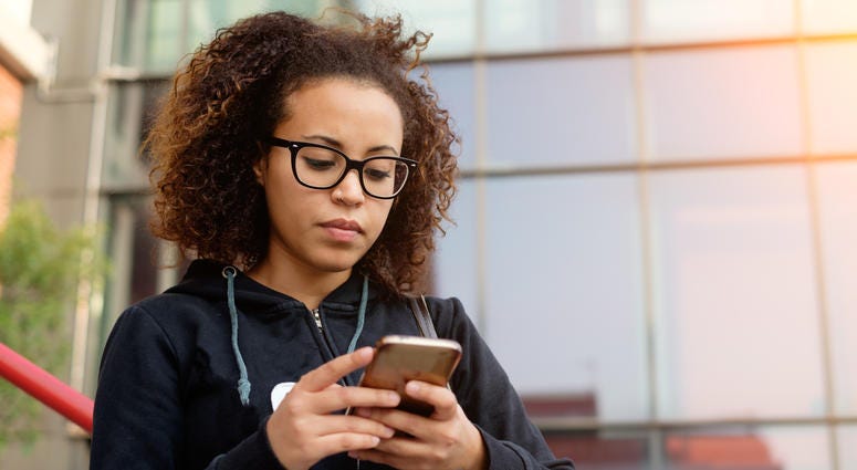 Young millennial girl texting on her mobile phone
