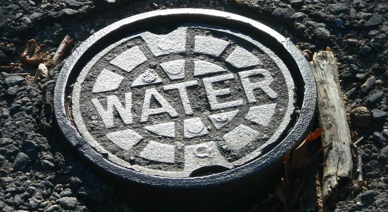 water main Cast iron water main manhole cover in potholed road