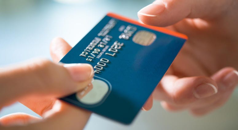 credit card Closeup shot of a women passing a payment credit card to the seller. Girl holding a credit card. Shallow depth of field with focus on the credit card.
