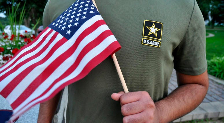 In this Tuesday, July 3, 2018, photo, a Pakistani recruit, 22, who was recently discharged from the U.S. Army, holds an American flag as he poses for a picture.