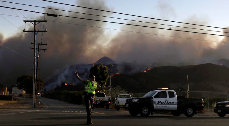A police officer mans a checkpoint in front of an advancing wildfire Thursday, Nov. 8, 2018, near Newbury Park, Calif. A police officer mans a checkpoint in front of an advancing wildfire Thursday, Nov. 8, 2018, near Newbury Park, Calif.