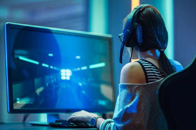 Gamer Convulsionándose En El Reino Unido Es Salvado Por Jovencita Gamer Desde Texas Shot of the Beautiful Pro Gamer Girl Playing in FPS Video Game on Her Personal Computer, Casual Cute Geek wearing Glasses and Headset. Neon Room. Online Cyber Games Internet Championship Event.