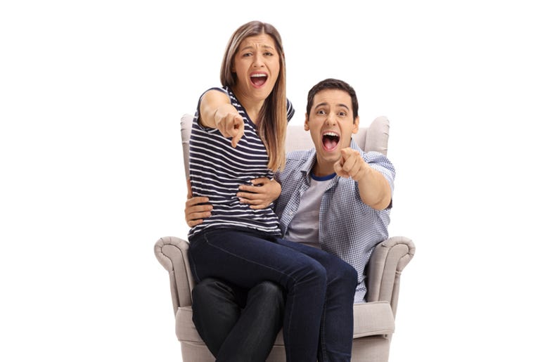 Hombres Vs Mujeres En El Nuevo Chair Challenge De Internet Happy young couple in an armchair pointing at the camera and laughing isolated on white background