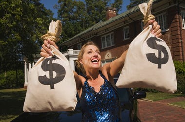 La Mujer Más Rica Del Mundo Vive En Fort Worth Woman with money bags in front of mansion - stock photo