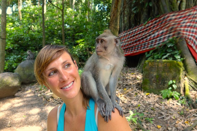 Mono Hace Que Turista Neozelandesa Enseñe La Boobie Young Caucasian traveler looking at little macaque on her shoulder. - stock photo