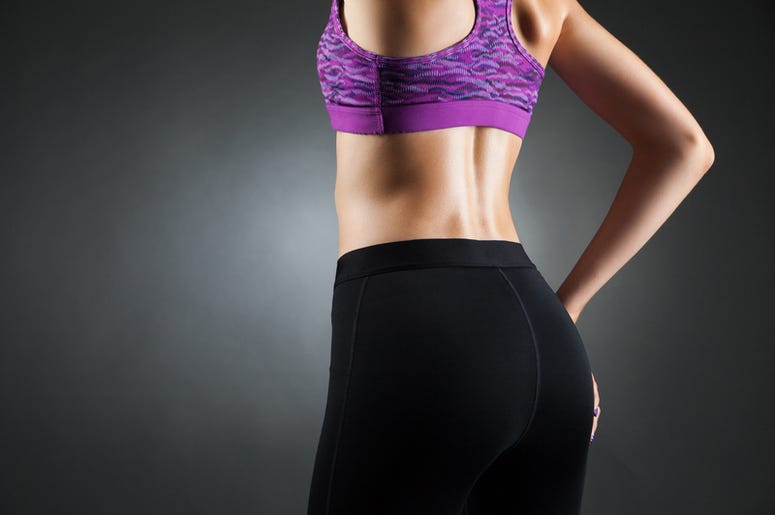 Licras Con Bolsillos Para Guardar Pistolas, Son Creadas En Dallas Fit sportswoman with in black yoga pants and purple top, back view. Studio portrait black background.