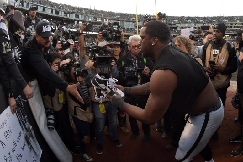 Oakland Raiders defensive end Clelin Ferrell (96) gives his cleats to a fan after the Raiders final game against the Jacksonville Jaguars at the Oakland-Alameda Coliseum before relocating to Las Vegas...