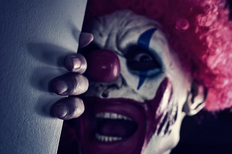 Closeup of a scary evil clown wearing a red hair wig, peering out from the corner Closeup of a scary evil clown wearing a red hair wig, peering out from the corner