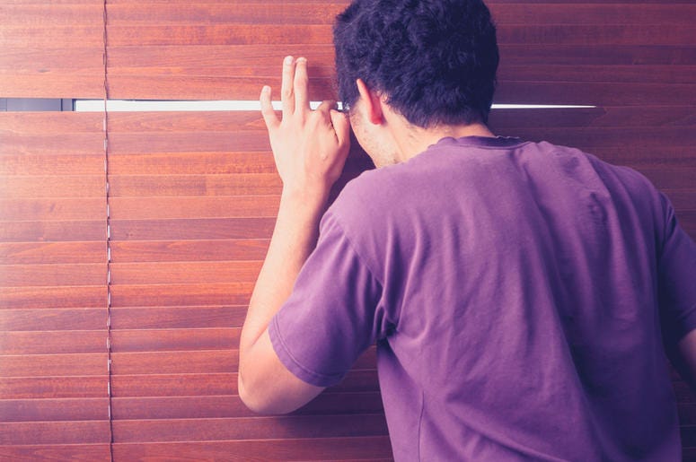 Young man is peeping out through the venetian blinds in his room Young man is peeping out through the venetian blinds in his room
