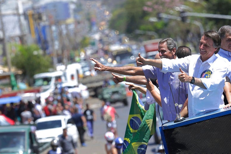Jair Bolsonaro flashes thumbs up at passersby in Brasilia's Ceilandia neighborhood