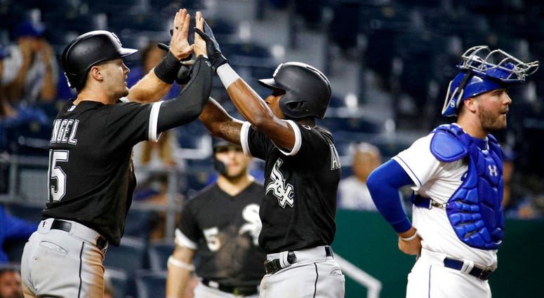 Chicago White Sox's Tim Anderson, center, celebrates with Adam Engel (15) as he crosses the plate past Kansas City Royals catcher Cam Gallagher after hitting a two-run home run during the 12th inning