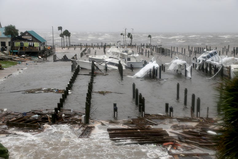Storm Surge retreats from inland areas, foreground, where boats lay sunk and damaged at the Port St. Joe Marina
