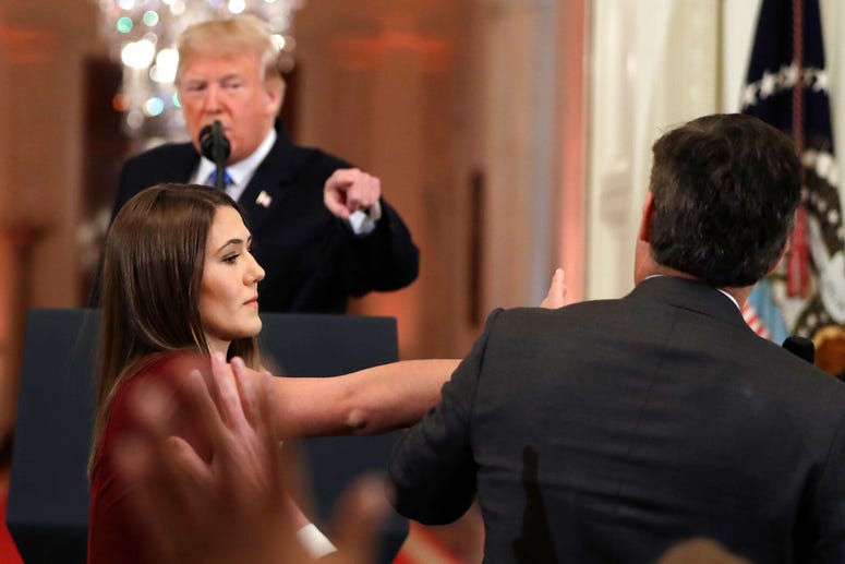 President Donald Trump looks on as a White House aide takes away a microphone from CNN journalist Jim Acosta during a news conference in the East Room of the White Hous