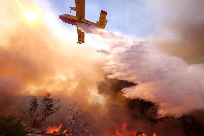 An air tanker drops water on a fire along the Ronald Reagan (118) Freeway in Simi Valley, Calif.