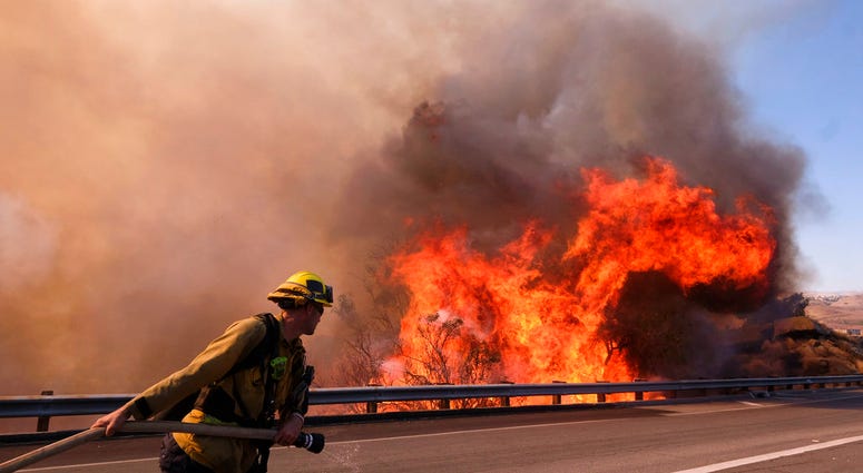 A firefighter battles a fire along the Ronald Reagan (118) Freeway in Simi Valley, Calif.