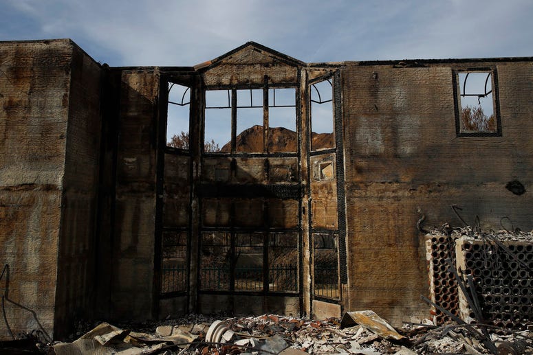 A mountain is seen through charred window frames of a mansion burned down by the Woolsey Fire