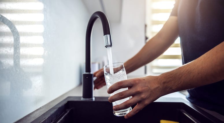 Close up of man pouring water from kitchen sink