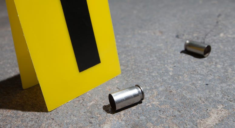 Evidence marker next to two empty handgun cartridges on concrete