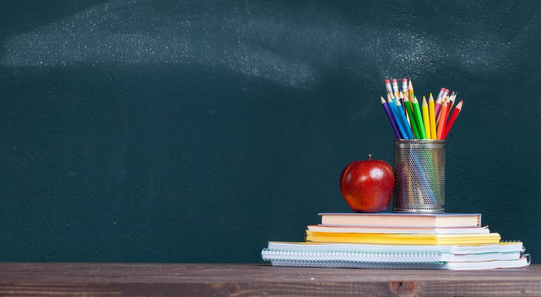 Pencil tray and an apple on notebooks on school teacher's desk