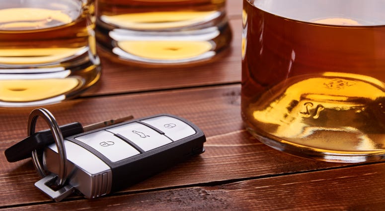 Car keys, several glasses and a bottle of whiskey or alcohol