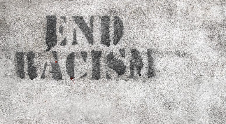 Graffiti on brick wall reads END RACISM