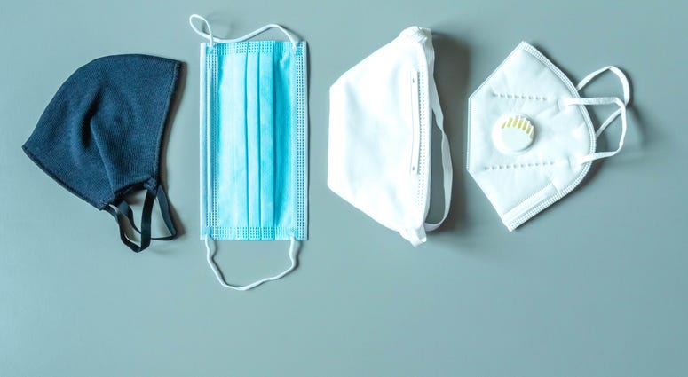 Different face masks and respirator on blue background