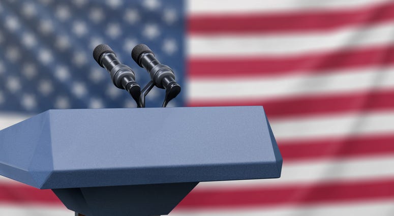 Podium lectern with two microphones and United States flag in background