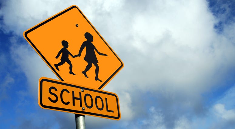 Yellow school road sign against a blue cloudy sky