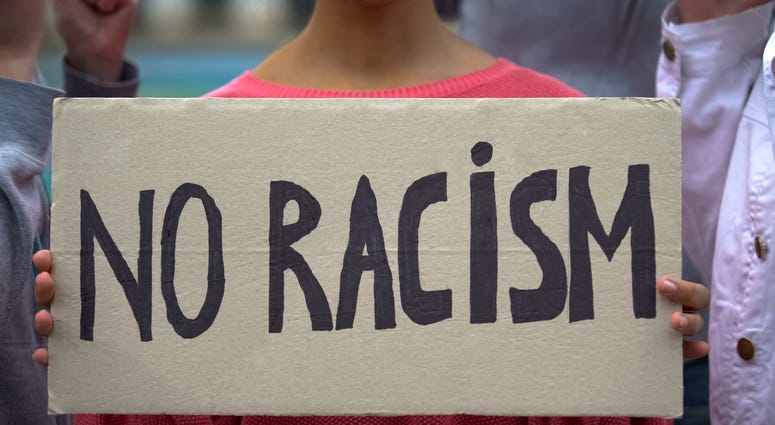 Girl holds sign reading 'No racism'
