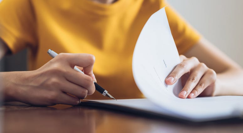 Woman signing document and hand holding pen