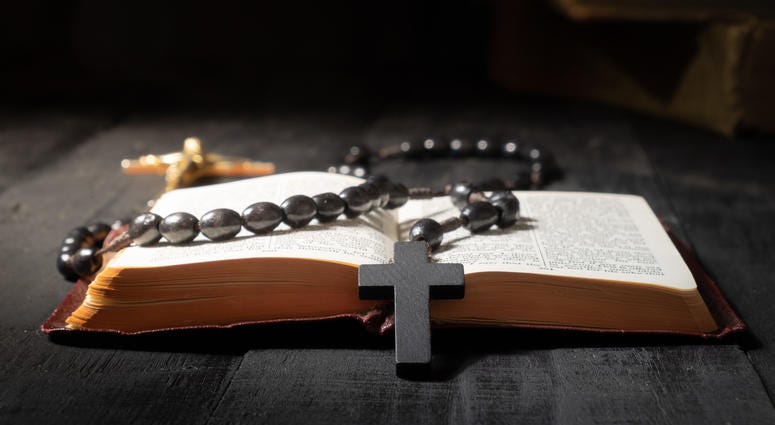 Flat lay image of New Testament, cross and rosary