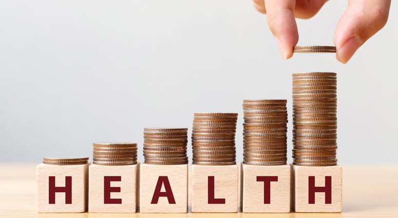 Hand putting coins on stack stair as step growing growth and wooden cube block with word HEALTH
