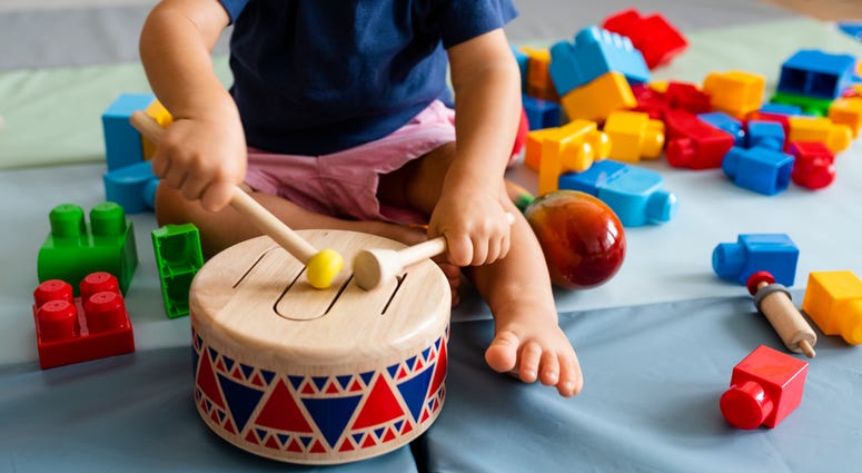 Little boy playing with wooden toy drum